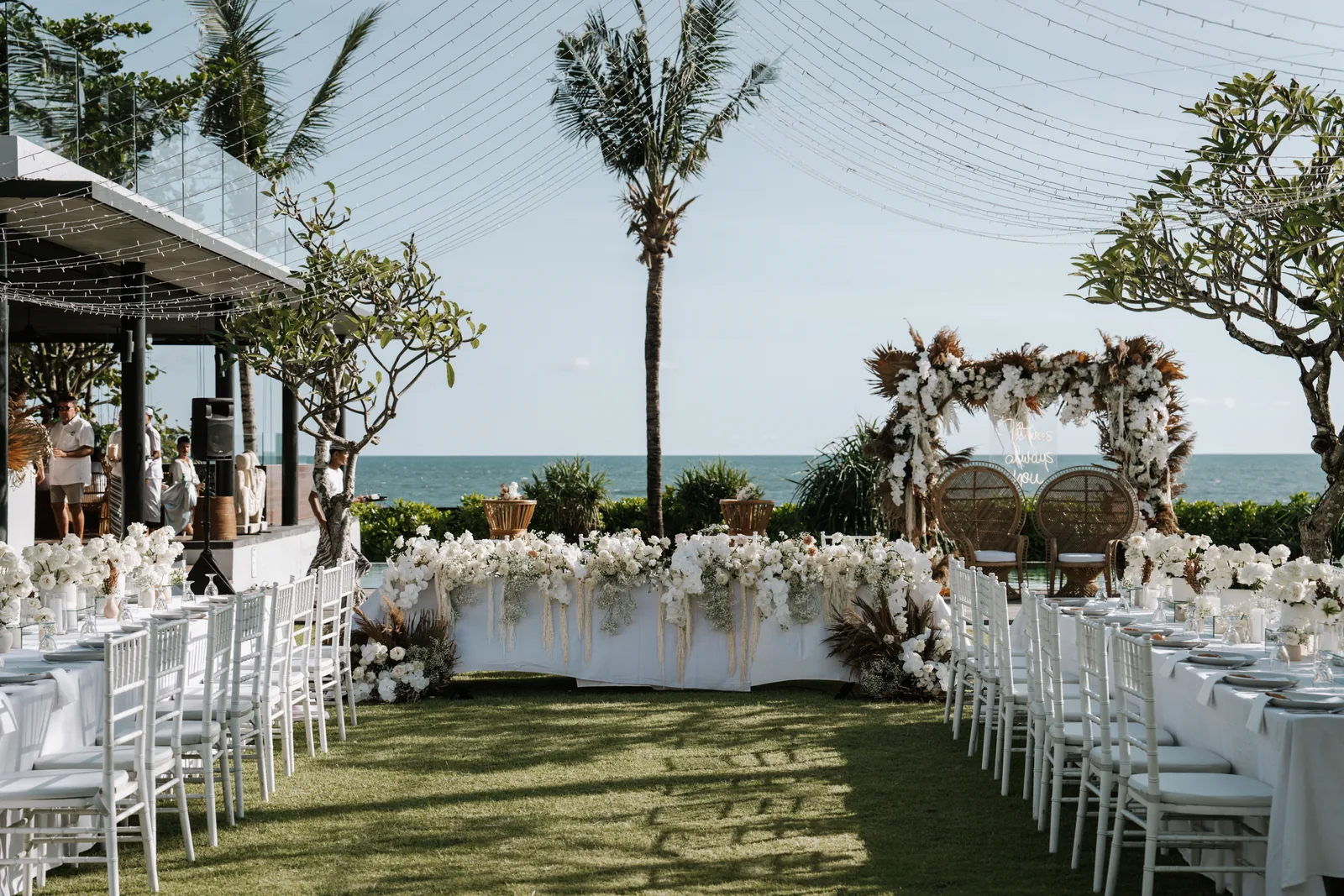 Long tables set on the lawn at Arnalaya Beach House, the beach house and ocean behind