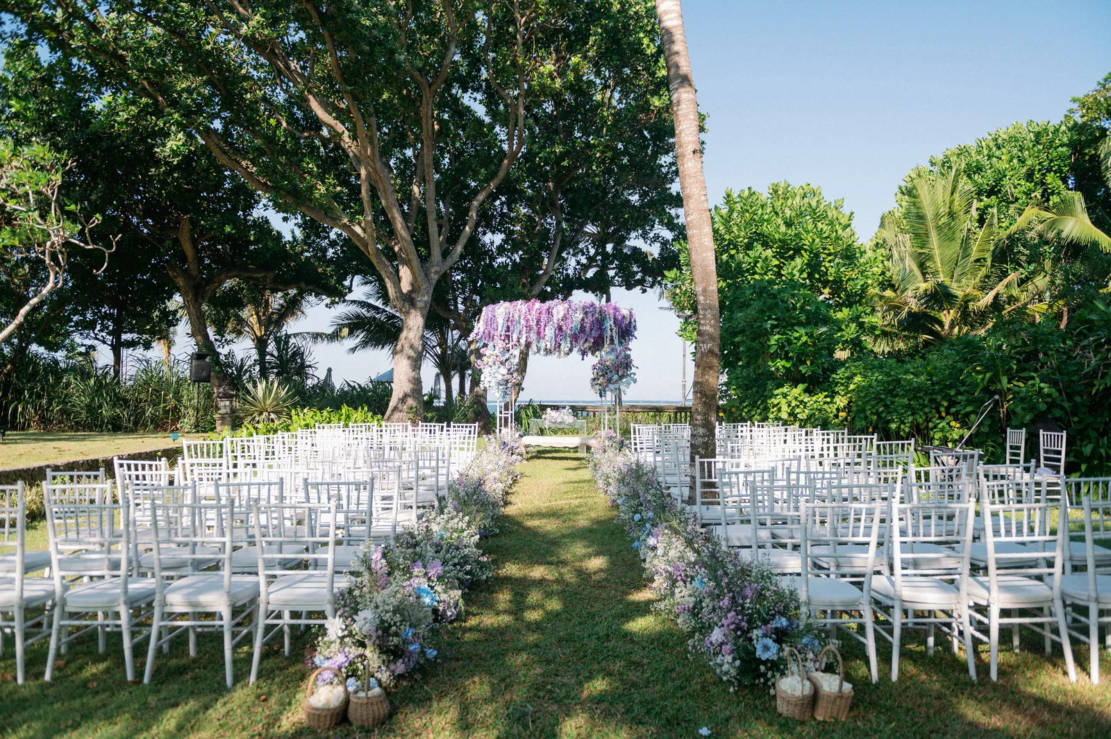 Chairs set for a garden ceremony at Hyatt Regency Bali, the floral canopy at the head of the aisle