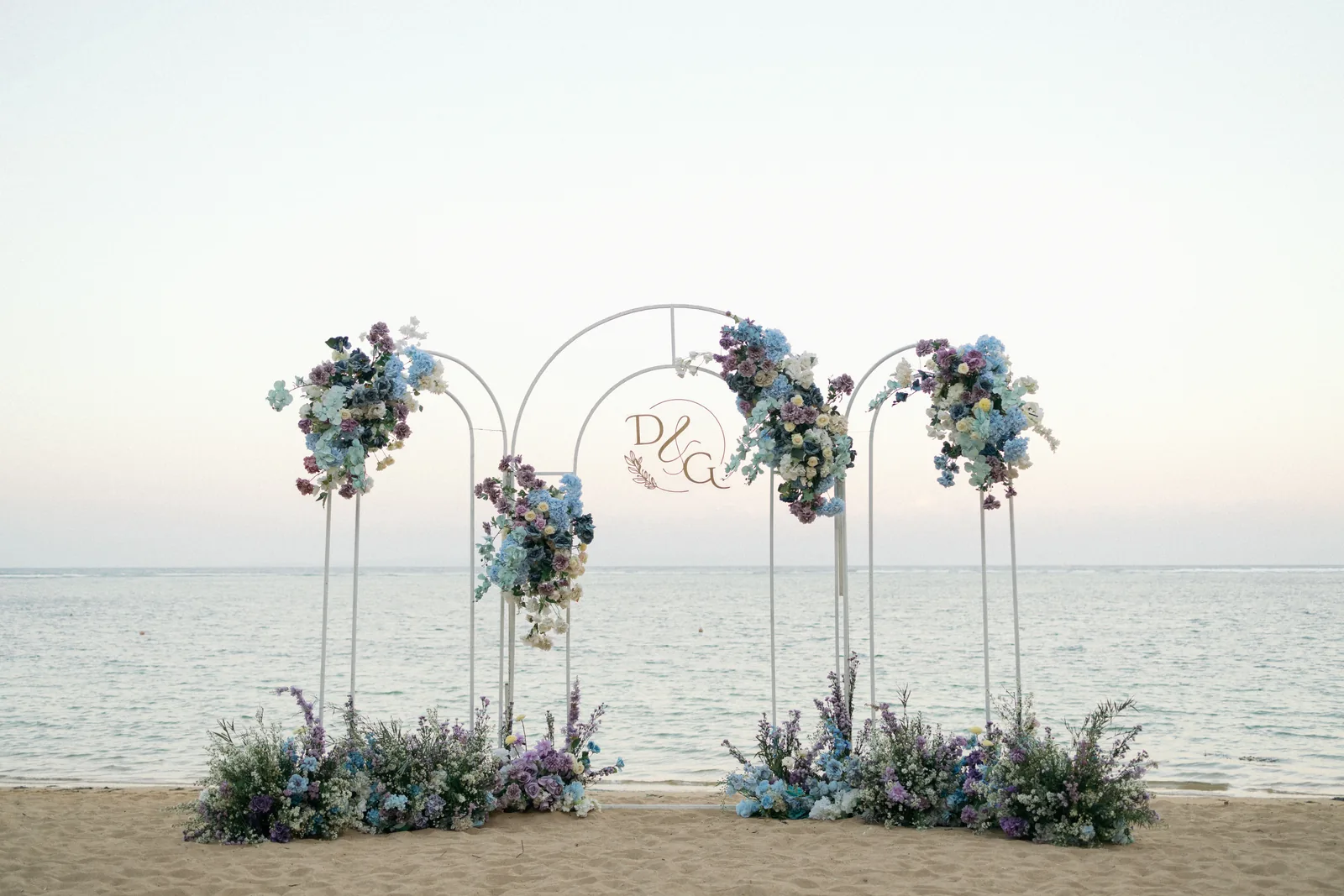A floral arch set on the sand at Hyatt Regency Bali at dusk