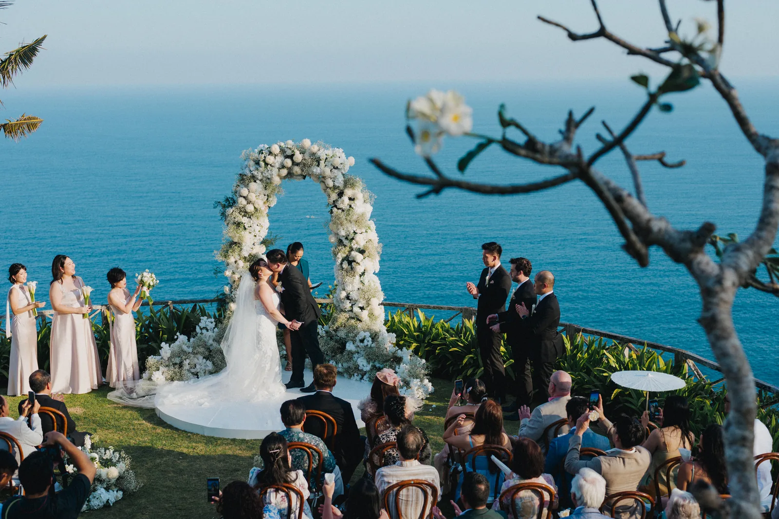 The floral arch at Khayangan Estate set on the cliff edge, guests looking on