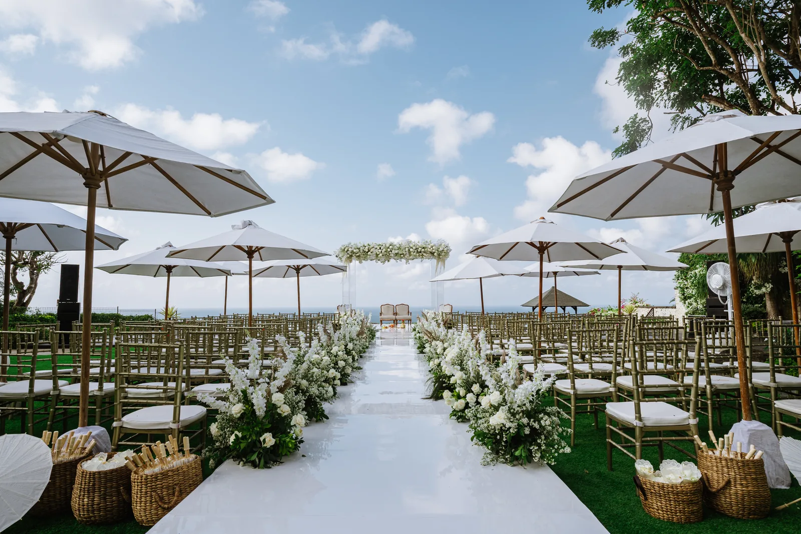 The ceremony aisle at Pandawa Cliff Estate set with parasols and florals under an open sky