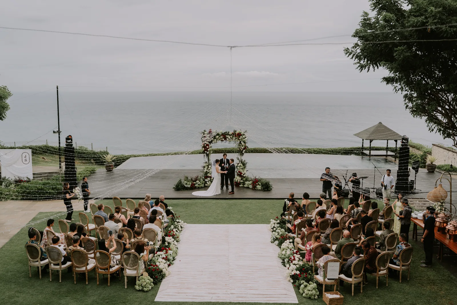 Guests seated for a clifftop ceremony at Pandawa Cliff Estate, the floral arch set at the cliff edge above the Indian Ocean