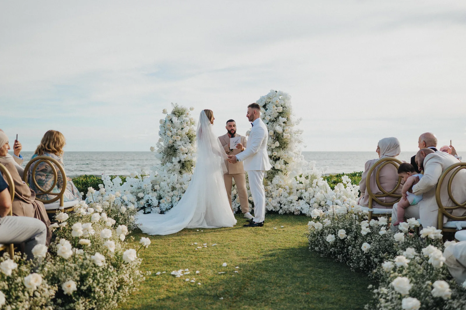 A couple at the floral altar at Phalosa Villa with the ocean behind them