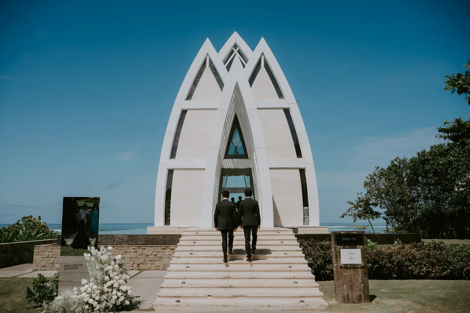 The Ritz-Carlton Bali's cliff-top glass chapel under a clear blue sky, the ocean beyond