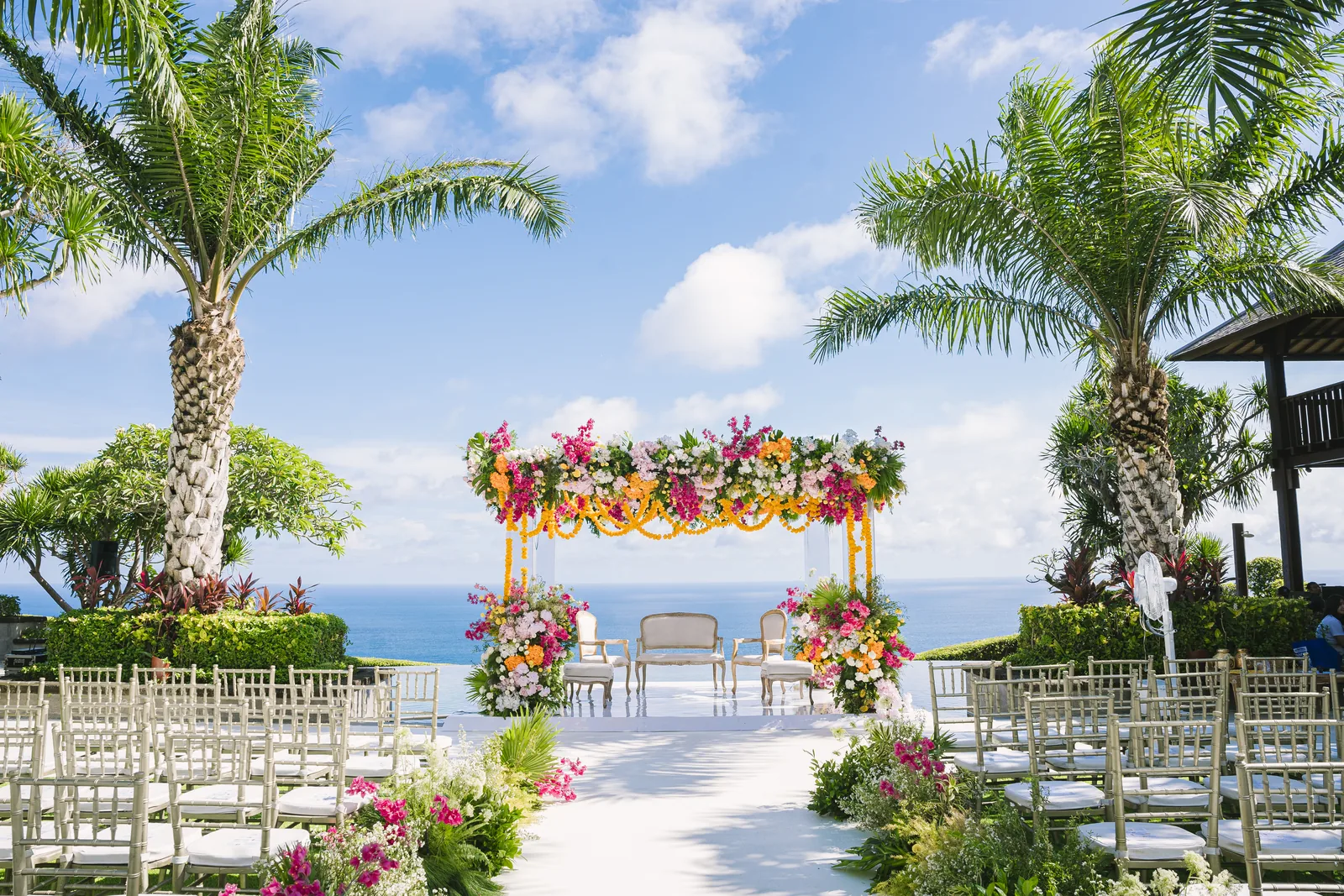 Chairs set either side of the aisle at Stones Villas Uluwatu, palms above and the Indian Ocean beyond