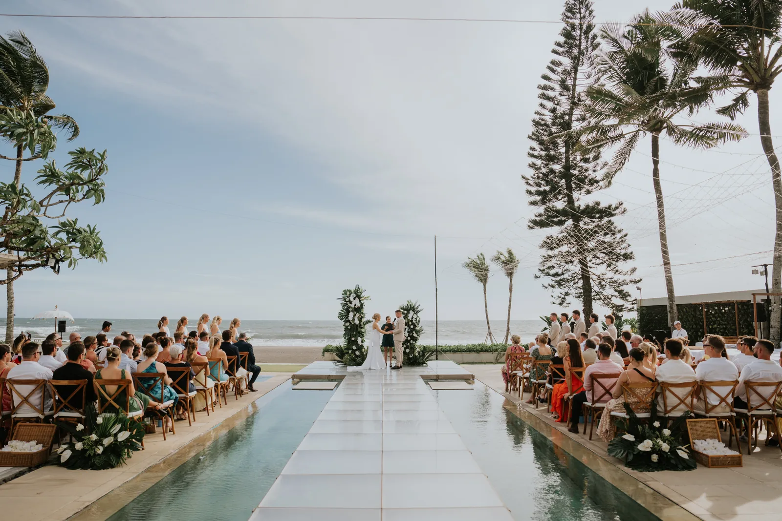 Guests seated for a beachfront ceremony at Villa Vedas, palms leaning over the aisle